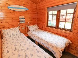 um quarto com 2 camas num chalé de madeira em Touchwood Lodge em Stepaside