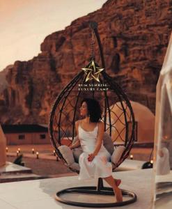 a woman sitting in a hanging chair in the desert at RUM SUNRlSE LUXURY CAMP in Wadi Rum