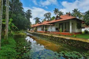 a house next to a river with lilies at Palmgrove Lake Resort in Alleppey