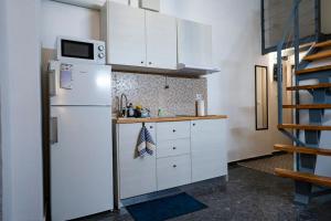 een keuken met witte kasten en een witte koelkast bij LoftLiving 1 by ΑΤΤΙΚΟ ΝΟΣΟΚΟΜΕΙΟ in Athene