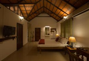 Schlafzimmer mit einem Bett, einem Schreibtisch und einem TV in der Unterkunft Palmgrove Lake Resort in Alappuzha