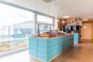une cuisine avec des placards bleus et une grande fenêtre dans l'établissement B&B HOTEL Lausanne Crissier, à Lausanne