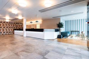 an office lobby with a reception desk and a chair at B&B HOTEL Lausanne Crissier in Lausanne