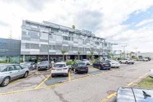 um parque de estacionamento com carros estacionados em frente a um edifício em B&B HOTEL Lausanne Crissier em Lausana