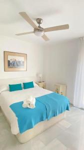 トレ・デル・マールにあるFabuloso apartamento a 50m de playa centricoのベッドルーム1室(青いシーツと天井ファン付きのベッド1台付)