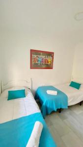 トレ・デル・マールにあるFabuloso apartamento a 50m de playa centricoのベッド2台が備わる部屋、壁に絵が飾られた部屋