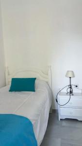 トレ・デル・マールにあるFabuloso apartamento a 50m de playa centricoの白いベッド(青い枕、ランプ付)