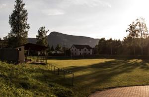 um campo de relva com uma casa e uma montanha em Restaurace Na Křižovatce em Božanov