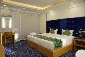 a bedroom with a large bed with a blue headboard at UB Grand Hotel in Ulaanbaatar