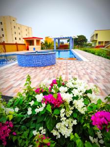 een tuin met roze en witte bloemen naast een zwembad bij Saikat Saranya Resort, #Mandarmoni #Beach in Mandarmoni