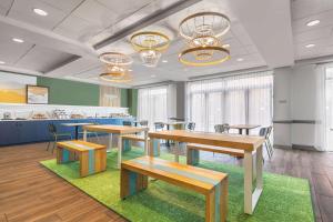 a cafeteria with tables and benches in a room at Spark By Hilton Charlotte Tyvola I-77 in Charlotte
