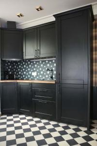 eine Küche mit schwarzen Schränken und einem karierten Boden in der Unterkunft Appartement prestige à deux pas de Montparnasse 6P in Paris