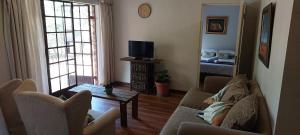 a living room with a couch and a tv at Cicada's Call Guest Cottage in Nelspruit