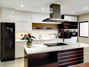 uma cozinha com armários brancos e um frigorífico preto em 4 on Pritchard Luxury Suites em Joanesburgo