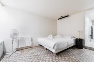 a white bedroom with a bed and a fan at Séjour romantique avec bain à remous à Pigalle -P6 in Paris
