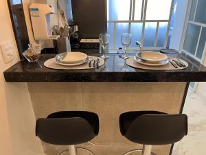 - un comptoir de cuisine avec 2 chaises, des assiettes et des verres dans l'établissement Studio Metrô Carioca, Lapa, SDU, Rodoviária, Consulado, à Rio de Janeiro