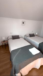 2 camas en una habitación con paredes blancas en PortoHome II, en Portomarín