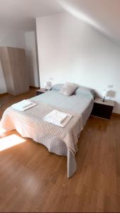uma cama grande num quarto com piso em madeira em PortoHome II em Portomarín