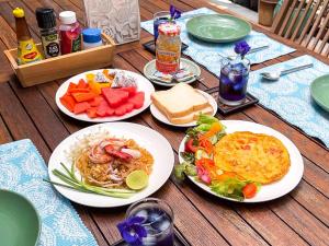 a wooden table with plates of food on it at Baleeyan Residence in Thalang