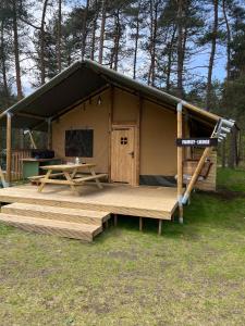 eine Hütte mit einer Holzterrasse und einem Picknicktisch in der Unterkunft Glampingzelt Family - Lodge in Soltau