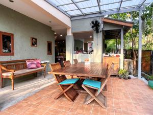 Une table et des chaises en bois sont disponibles sur la terrasse. dans l'établissement Baleeyan Residence, à Thalang