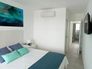 a white bedroom with a bed with blue pillows at Nunoli Duplex Luxury Playa Blanca in Playa Blanca