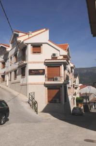 a large white building with a car parked in front of it at Edificio Reyes in La Adrada