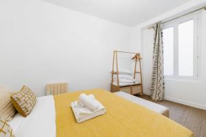 een witte slaapkamer met een bed met handdoeken erop bij Jolie 2 pieces 35m2 bien équipée 4P - Paris 20 in Parijs