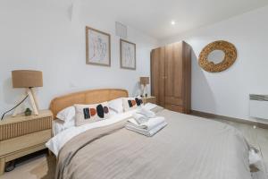 una camera da letto con letto, lenzuola e cuscini bianchi di Espace moderne 40m2 a deux pas de Paris - 4P a Les Lilas