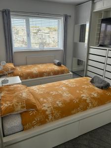 1 dormitorio con 2 camas y espejo en Garreg Fawr Trearddur Bay - Ty Melyn, en Trearddur