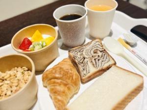 um prato de comida com pão e frutas e chávenas de café em Henn na Hotel Fukuoka Hakata em Fukuoka