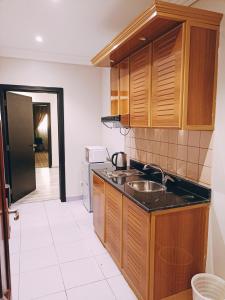 a kitchen with wooden cabinets and a sink at Alhamra Park hotel in Jeddah