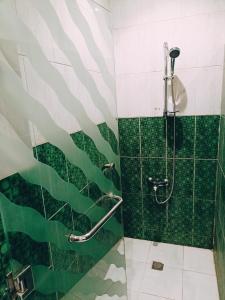 a bathroom with a shower with green tiles at Alhamra Park hotel in Jeddah