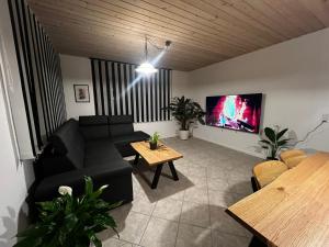a living room with a black couch and a tv at Cozy Rødbyhavn Villa - Lalandia/Puttgarden/Femern in Rødby