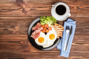a plate of eggs and bacon and toast with a cup of coffee at Horizon Boutique in Samarkand