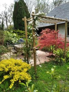 un jardín con flores de colores y pérgola de madera en Maison dans un environnement boisé très calme en Morlaix