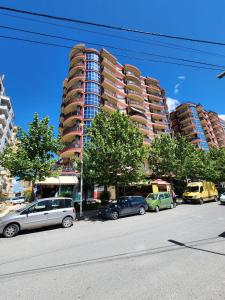 a parking lot with cars parked in front of a tall building at Onis Apartment in Vlorë
