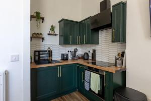 a kitchen with green cabinets and a counter top at Spacious 3 Bedroom Home In Glasgow - Free Parking in Glasgow