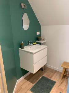 a bathroom with a white sink and a green wall at Les chambres de Christelle & Gilbert in Margon