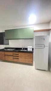 eine Küche mit einem weißen Kühlschrank und Holzschränken in der Unterkunft Apto JP 301 para 2 pessoas in Vitória