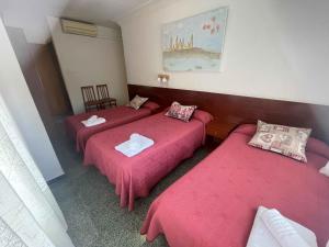 サラゴサにあるHostal Cumbreのピンクのシーツが備わる客室内のベッド3台