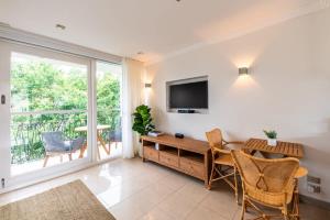 een woonkamer met een televisie en een tafel en stoelen bij Riverside Studio apartment with parking in Brisbane