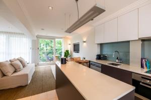 een keuken en een woonkamer met een bank bij Riverside Studio apartment with parking in Brisbane