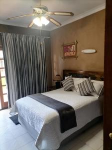a bedroom with a bed and a ceiling fan at Lions Rest Guest House and Conference Centre Germiston in Germiston +17 photos