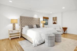 a white bedroom with a large bed and a chair at Dos Palos by AvantStay Mod Hollywood Sanctuary in Los Angeles