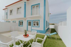 a white and blue house with a table and chairs at Best Houses 105 - A Vivenda in Atouguia da Baleia