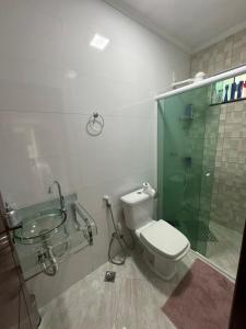 a bathroom with a glass shower and a toilet at Casa bosque in Papuda