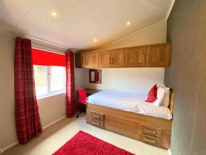 a bedroom with a bed and a window with red curtains at Benarty 11 with Private Hot Tub - Fife - Loch Leven - Lomond Hills - Pet Friendly in Kelty