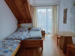 a bedroom with two beds and a table and a window at Spiska Sadyba in Łapsze Niżne