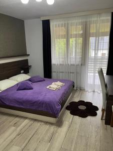 - une chambre avec un lit violet et une fenêtre dans l'établissement Guesthouse Villa Plitvička, aux lacs de Plitvice